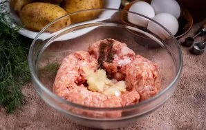 Visą maltą mėsą sudėkite į dubenį, smulkiai sutarkuokite svogūną, įberkite druskos (1/2 arb. šaukštelio) ir maltų juodųjų pipirų.