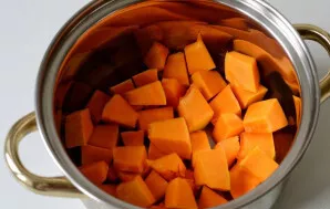 Moliūgą supjaustykite kubeliais ir sudėkite į puodą.