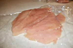 Ant darbinio paviršiaus padėkite vištienos krūtinėlės gabalėlį ir maistinę plėvelę. Uždenkite kitu maistinės plėvelės sluoksniu ir švelni...