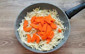 Nulupkite ir supjaustykite morkas. Sudėkite jas į keptuvę su kopūstais ir troškinkite dar 5 minutes.