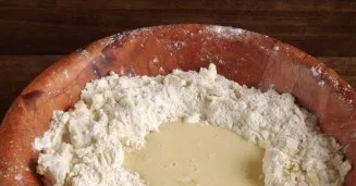 Supilkite gautą masę į miltų ir sviesto duobutę. Gerai sumaišykite visus ingredientus ir minkykite elastingą tešlą.
