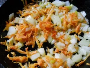 Keptuvėje pakepinkite tarkuotas morkas ir smulkintus svogūnus iki auksinės rudos spalvos.