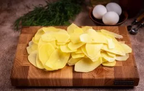 Nulupkite bulves, nuplaukite jas ir supjaustykite plonais griežinėliais.