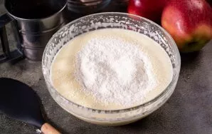 Dabar į šį purų kiaušinių mišinį po truputį persijokite miltus ir mentele maišykite, kol mišinys visiškai susijungs.