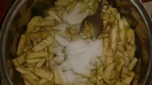 Nuluptą baklažaną supjaustykite. Sudėkite jį į daržoves kartu su druska ir cukrumi. Viską sumaišykite ir palikite 15 minučių.